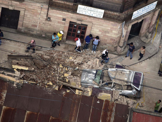 Residents walk around rubble and a car damaged after a magnitude 7.4 earthquake struck in San Marcos, Guatemala, Wednesday Nov. 7, 2012. 