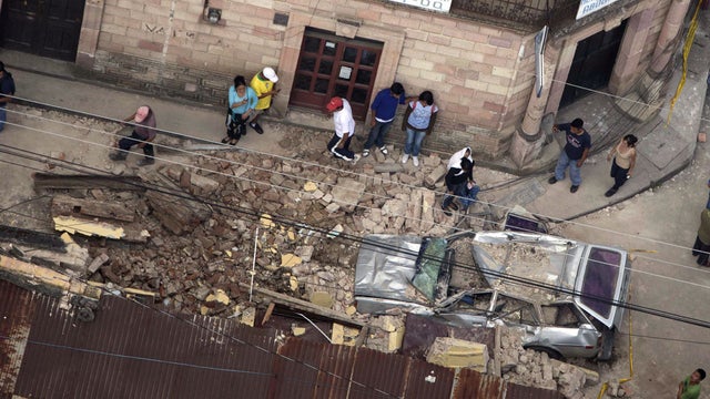 Residents walk around rubble and a car damaged after a magnitude 7.4 earthquake struck in San Marcos, Guatemala, Wednesday Nov. 7, 2012. 