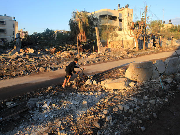 A Palestinian boy pushes a bicycle through rubble in an area targeted by an Israeli air strike in Gaza City 