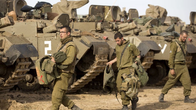 Israeli soldiers next to armored personnel carriers stationed on Israel's border with the Gaza Strip 