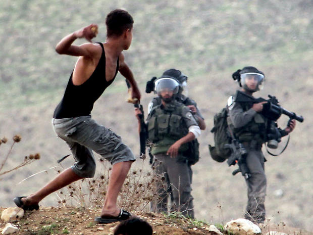 A Palestinian youth throws a rock at Israeli soldiers during clashes in the West Bank town of Nablus, on November 18, 2012, as Palestinian across the territories protest against Israel's military action on the Gaza Strip. 