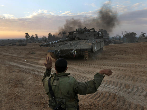 An Israeli soldier guides a tank to a new position at a staging area near the Israel-Gaza Strip border 