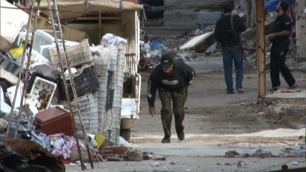 A Syrian ducks while passing through a dangerous part of Baba Amr in Homs, Syria. 
