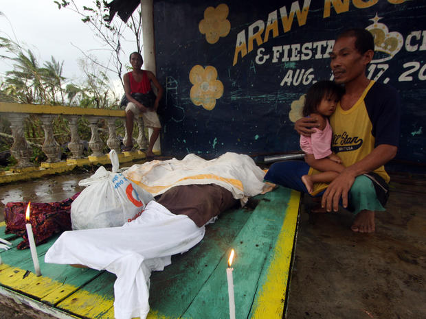 A man looks at the dead bodies of relatives killed by landslides after Typhoon Bopha 