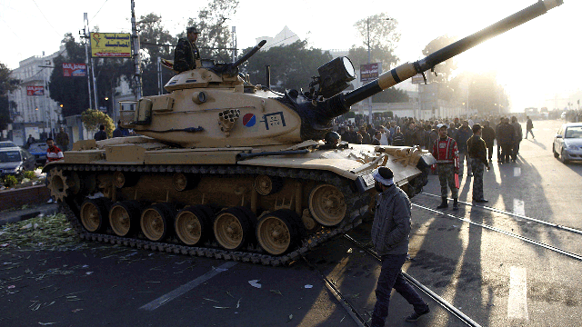 Egyptians walk past army tanks deployed near the presidential palace in Cairo after five demonstrators died overnight in clashes between supporters and opponents of Islamist President Mohamed Morsi on December 6, 2012.  