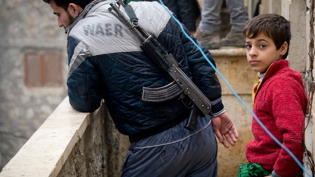 A Rebel fighter looks at a demonstration against the Syrian regime from his balcony 