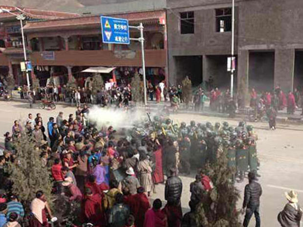 Chinese troops surround Dorje Rinchen as he lays on the ground after setting himself on fire 
