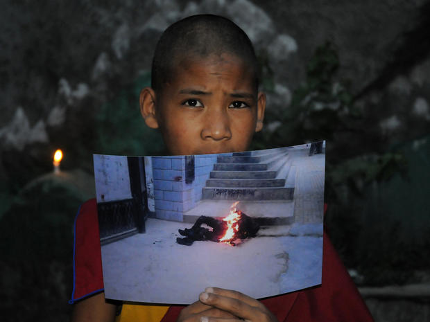 An exiled Tibetan monk holds a picture of 50-year-old, Tamdin Thar, who burned himself to death 