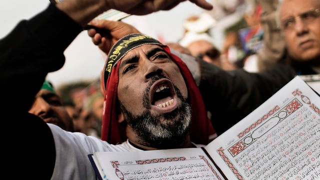 A supporter of Egypt's President Mohamed Morsi and the Muslim Brotherhood holds a copy of the Koran, Islam's holy book, as he shouts slogans during a demonstration in Cairo's Nasr City on December 14, 2012.  