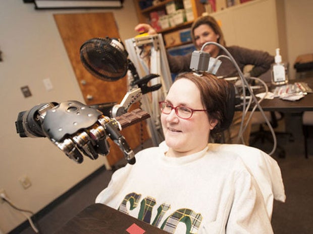 Jan Scheuermann, who has quadriplegia, brings a chocolate bar to her mouth using a robot arm she is guiding with her thoughts.