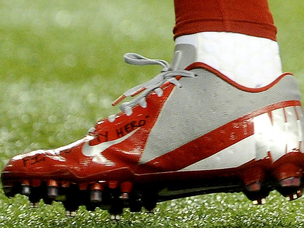 in this Sunday, Dec. 16, 2012, photo, a shoe worn by New York Giants wide receiver Victor Cruz bears a message dedicated to 6-year-old Jack Pinto, one of the victims in last week's school shootings at Sandy Hook Elementary School in Newtown, Conn., as Cruz warms up for the Giants' NFL football game against the Atlanta Falcons in Atlanta. 