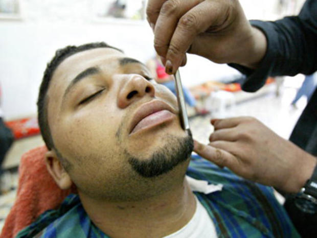 An Iraqi customer gets his beard trimmed 