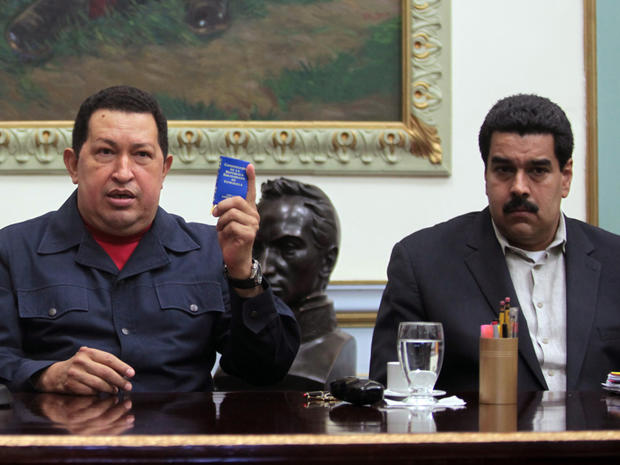In this Dec. 8, 2012, file photo released by Miraflores Press Office, Venezuela's President Hugo Chavez, left, holds up a copy of the Venezuelan national constitution as his Vice President Nicolas Maduro looks on during a televised speech at Miraflores presidential palace in Caracas, Venezuela. Chavez has suffered "new complications" following his cancer surgery in Cuba, Maduro said Sunday, Dec. 30, 2012, describing the Venezuelan leader's condition as delicate. 