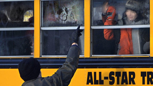 A man waves to a child on a bus on the first day of classes after the holiday break, in Newtown, Conn.,Wednesday, Jan. 2, 2013. 
