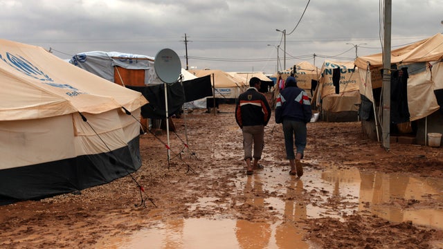Two Syrian refugees walk at a camp in Jordan 