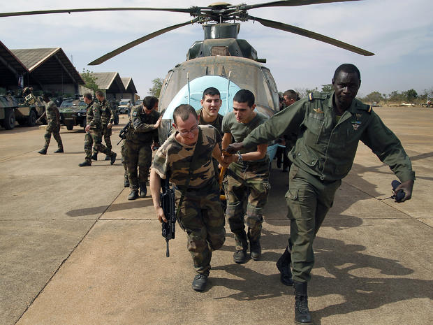 Malian soldiers helped by French troops move a broken helicopter out of a hangar to make room for more incoming troops at the airport in Bamako, Mali, Jan. 15. 2013. 