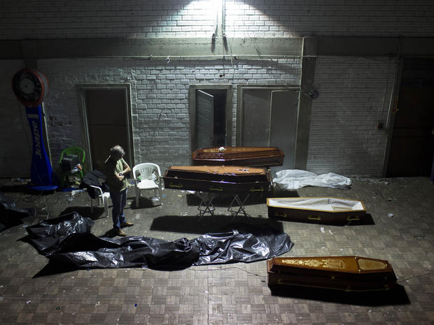 A man stands around coffins containing the remains of victims after the bodies were identified at a gymnasium in Santa Maria city, Rio Grande do Sul state, Brazil, Sunday, Jan. 27, 2013. A fast-moving fire roared through the crowded, windowless Kiss night 