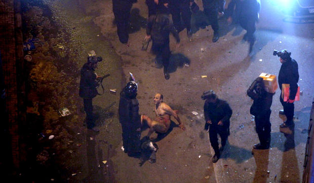 Egyptian riot police beat a man, after stripping him during clashes next to the presidential palace, Friday, Feb. 1, 2013, in Cairo. 