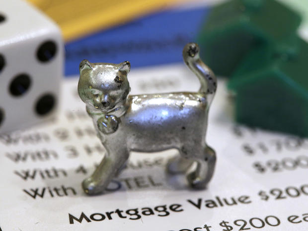 The newest Monopoly token, a cat, rests on a Boardwalk deed next to a die and houses at Hasbro Inc. headquarters, in Pawtucket, R.I., Tuesday, Feb. 5, 2013. Voting on Facebook determined that the cat would replace the iron token. 