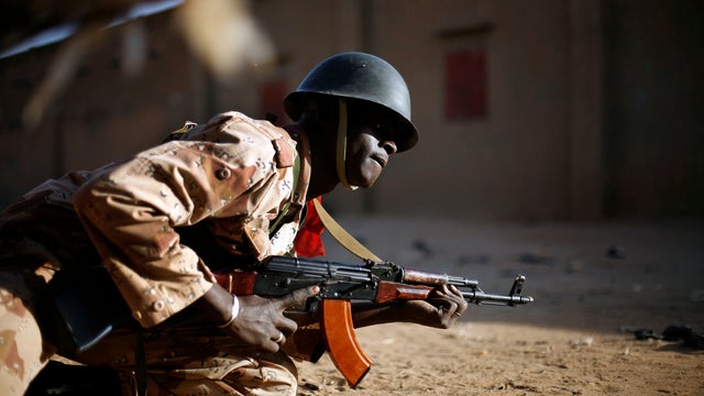 A Malian soldier takes cover behind a truck during exchanges of fire with jihadists in Gao, Mali, Feb. 10, 2013 