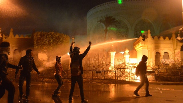 Egyptian security use water cannon as protesters throw stones into the grounds of the presidential palace in Cairo 