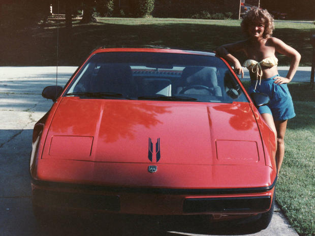 Tina poses with the first car she bought. 