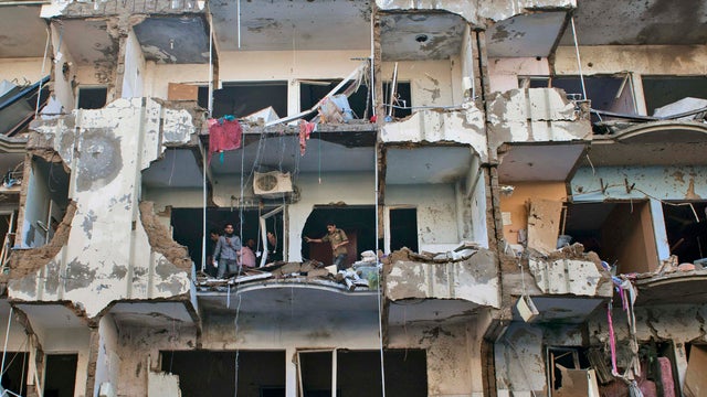 Pakistanis check damage to apartment building destroyed along with other buildings in car bombing in Karachi, Pakistan on March 4, 2013 that killed at last 45. Members of Pakistan's Shiite community were digging Monday through the rubble, looking for love 