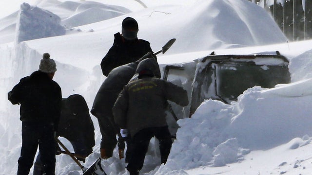 Photo taken March 3, 2013 shows policemen shoveling snow around vehicle of Kazuyo Miyashita along road in Nakashibetsu, Hokkaido, northern Japan. Kyodo news service says Miyashita and her three children died at a hospital Saturday night of carbon-monoxide 