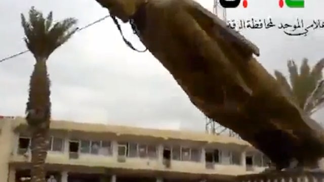 A statue of former Syrian President Hafez Assad being pulled down in a central square in Raqqa 
