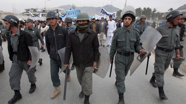 Afghan police surround several hundred demonstrators marching to the Afghan parliament building 