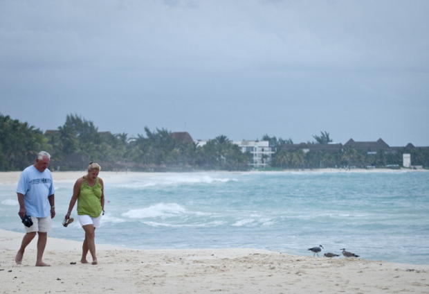 Tourists walk along the beach of Playa d 
