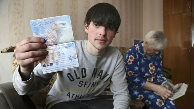 Add to Current Lightbox  In this photo taken on Saturday, March 20, 2013, Alexander Abnosov shows his American passport to journalists in the Volga river city of Cheboksary, Russia. His 72 -years old grandmother is in the background. Abnosov was adopted b 