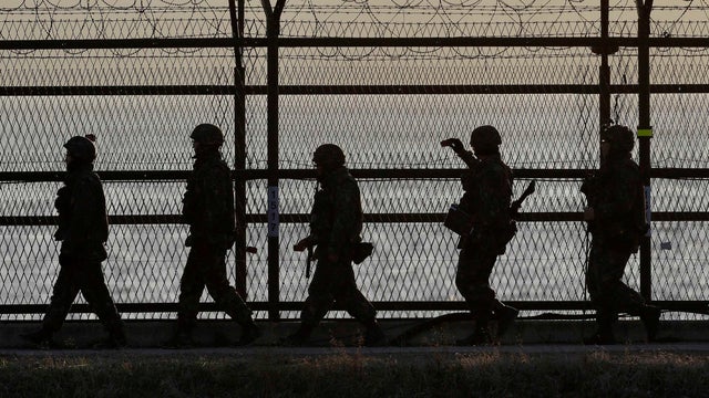South Korean army soldiers patrol along a barbed-wire fence at sunset near the border village of Panmunjom, which has separated the two Koreas since the Korean War, in Paju, north of Seoul, South Korea, Sunday, April 7, 2013.  