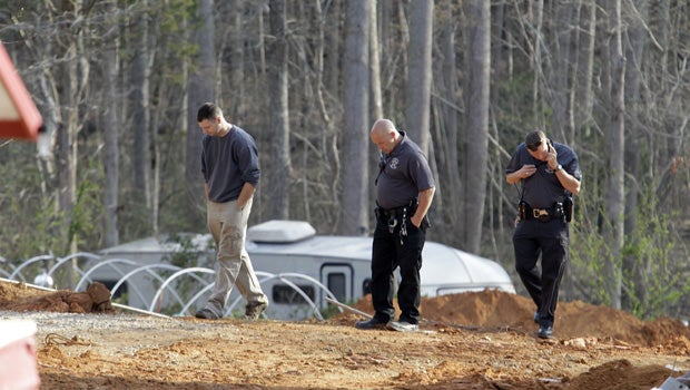 A man, left, walks with investigators Monday, April 8, 2013, around the scene of a collapsed construction site where two children died when the dirt walls collapsed Sunday on Cedarbrook Court in Stanley, N.C. 
