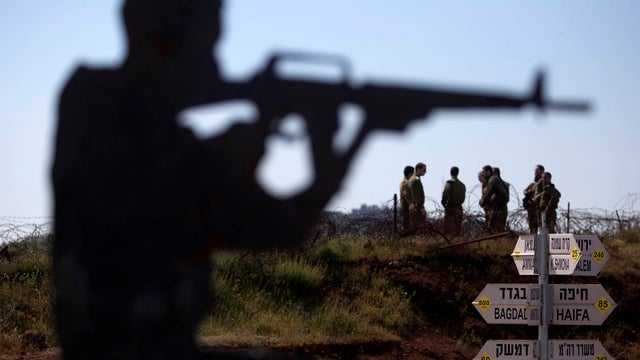 Israeli soldiers stand next to a metal placard in the shape of an Israeli soldier at an observation point on Mount Bental in the Golan Heights April 24, 2013. 