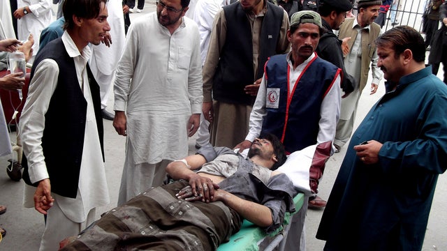 People stand near a man injured from an explosion, at a local hospital in Pakistani tribal area of Parachinar, Monday, May 6, 2013.  