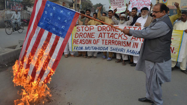 A demonstrator holds up a burning U.S. flag during a protest against drone attacks 