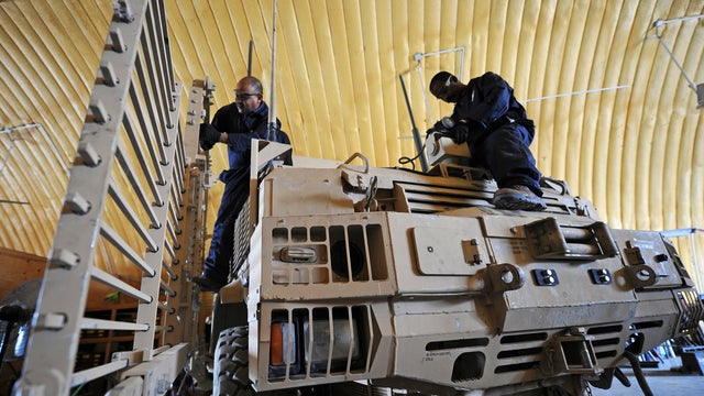 Workers from AC First company, a private contractor, repair a mine-resistant, ambush-protected (MRAP) vehicle at Camp Clark in Mandozai, Afghanistan, July 6, 2011. AC First is a private contractor tasked in repairing weapons and vehicles used by U.S. sold 