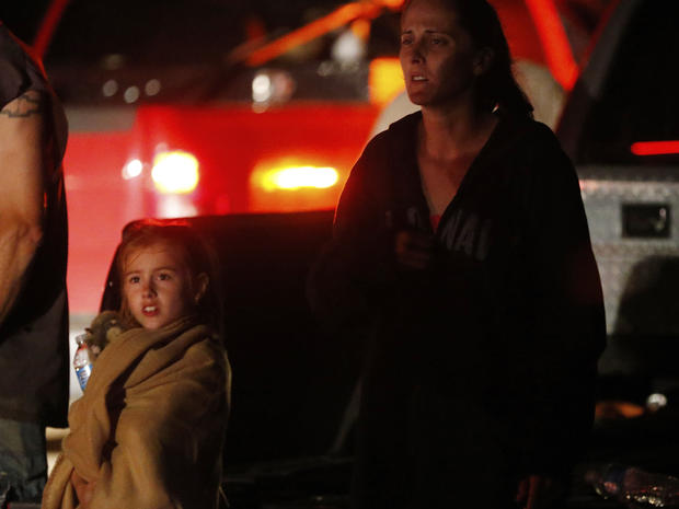 Seven-year-old Katrina Ash watches with her mother, Amber Ash, as heavy equipment is brought into their tornado damaged neighborhood 