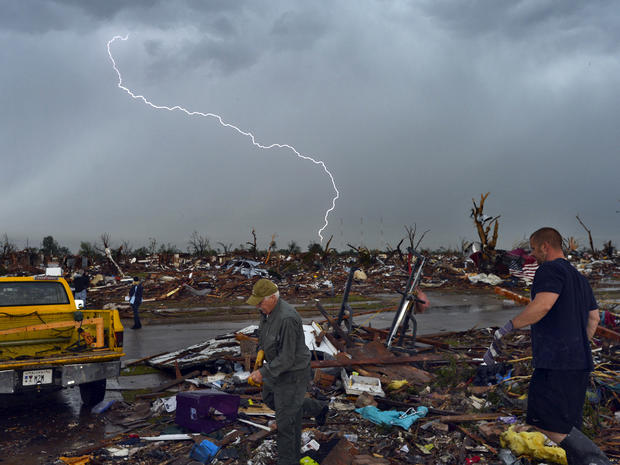 Lightning strikes during a thunderstorm as tornado survivors search for salvageable belongings at their devastated home May 23, 2013, in Moore, Okla. 