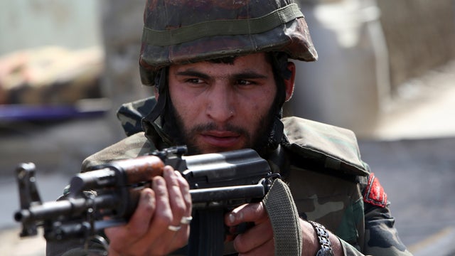 A Syrian army soldier aims his weapon during a battle against opposition fighters in the city of Qusayr, Syria, in Homs province, May 23, 2013. 