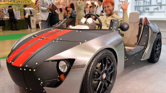 Japanese car designer Kota Nezu poses in Toyota Motor's concept model of a three-seater electric vehicle with a roadster body, called the "Camatte 57S" 