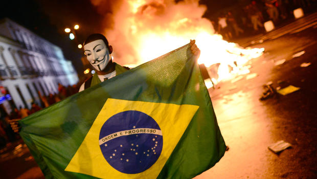 A demonstrator wearing a Guy Fawkes mask holds a Brazilian national flag during clashes in downtown Rio de Janeiro on June 17, 2013, after a protest against higher public transportation fares and the use of public funds to finance international football tournaments. 