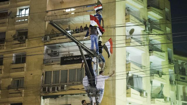 Protesters climb on a railway pole as hundreds of thousands of Egyptian demonstrators gather at the Egyptian Presidential Palace during a protest 