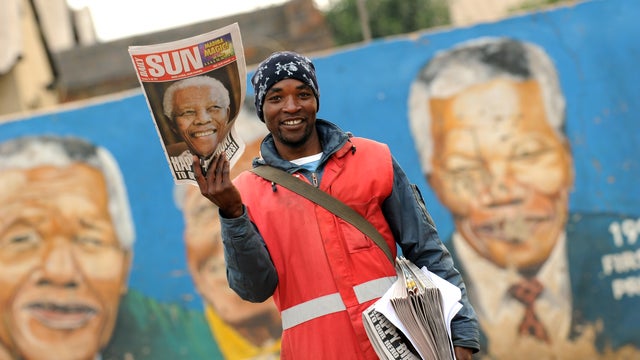 A newspaper vendor shows the front page of the local Daily Sun in Soweto, wishing former South African President Nelson Mandela a happy 95th birthday 