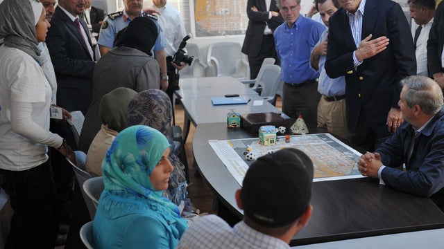 John Kerry greets a group of Syrian refugees during a joint meeting with Jordanian Foreign Minister Nasser Judeh (sitting, R) at the Zaatari refugee camp 