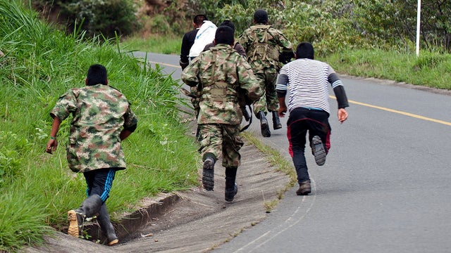 Revolutionary Armed Forces of Colombia (FARC) guerrillas run as the police nears, in the rural area of Caloto, department of Cauca, Colombia, on June 4, 2013, after putting mines along the road between Caloto and Toribio. 