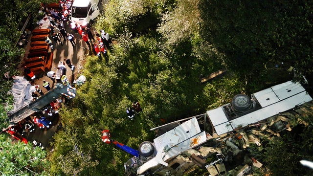 Coffins are lined up near wreckage of bus following crash near Avellino, southern Italy, early Monday, July 29, 2013 