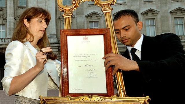 The Queen's Press Secretary Ailsa Anderson with Badar Azim, a footman, places an official document to announce the birth of a baby boy, at 4.24pm to the Duke and Duchess of Cambridge at St Mary's Hospital, in the forecourt of Buckingham Palace in London M 