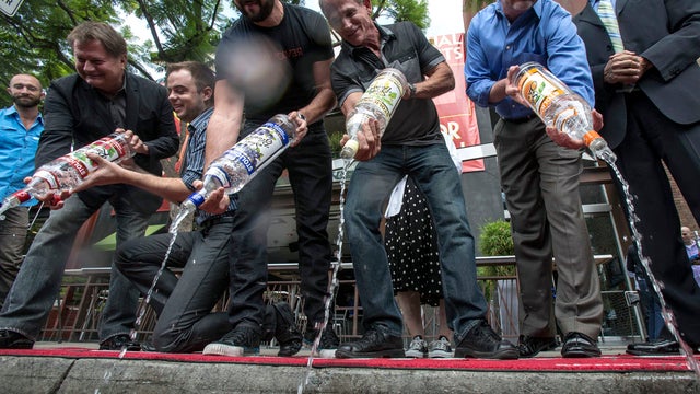 From left to right, Michael Niemeyer, Matthew Ervin, Alfredo Diaz, Richard Grossi, Rodney Scott and West Hollywood, Calif., council member John Duran empty Russian vodka bottles into a gutter during a news conference Aug. 1, 2013, in West Hollywood, Calif 